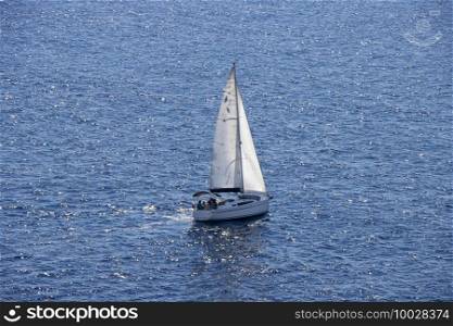 Sailingboat with white sails at opened sea