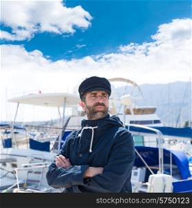 Sailor man in marina port with boats background and blue cap