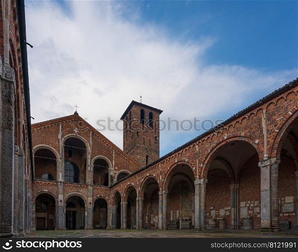 Saint Ambrogio church brick building with bell towers, courtyard, arches at overcast day, Milan, Lombardy, Italy