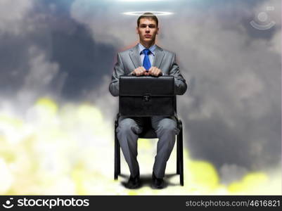 Saint businessman. Young businessman with halo above head sitting on chair