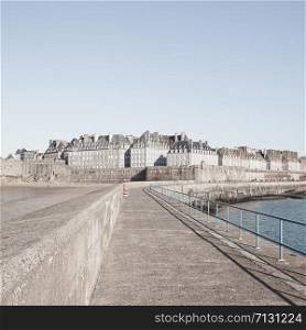 Saint Malo view of the walled city from the pier Mole des Noires. Ille et Vilaine, department of France, located in the region of Brittany. Pastel beige faded trendy toning. Square composition