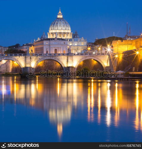 Saint Peter Cathedral at night in Rome, Italy.. Saint Angel bridge and Saint Peter Cathedral with a mirror reflection in the Tiber River during morning blue hour in Rome, Italy.