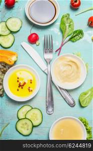 Salad and dressing ingredients with cutlery on on turquoise blue shabby chic background, top view. Healthy lifestyle or diet food concept