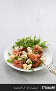 Salad arugula, Parma ham with sun-dried tomatoes, mozzarella slices, croutons, capers, seasoned oil and spices
