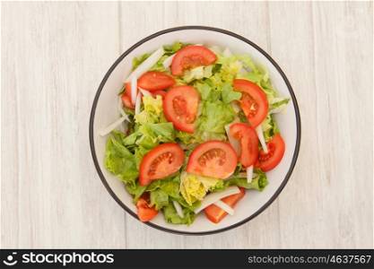 Salad bowl with lettuce tomato and onion on a white wooden background