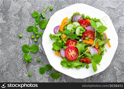 Salad. Fresh vegetable salad with tomato, onion, cucumbers, pepper, lettuce and green peas. Vegetarian salad with vegetables on plate