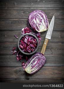 Salad from fresh cabbage in the bowl with the knife. On a wooden background.. Salad from fresh cabbage in the bowl with the knife.