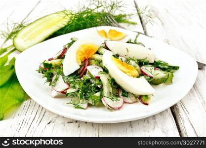 Salad from radishes, cucumber, sorrel, greens and eggs, dressed with mayonnaise and sour cream in a plate on the background of light wooden boards. Salad with radish and egg in plate on light board
