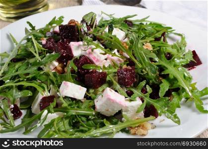 Salad from roasted beets, arugula, cheese feta, and walnuts. Horizontal shot. Foreground close-up.
