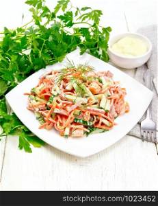Salad from smoked sausage, spicy carrot, tomato, cucumber and spices, dressed with mayonnaise, kitchen towel, fork and parsley on a light wooden board background