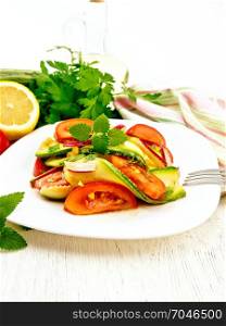 Salad from young zucchini, radish, tomato and mint flavored with lemon juice and soy sauce in a white plate, napkin on a wooden board background