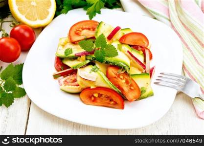 Salad from young zucchini, radish, tomato and mint flavored with lemon juice and soy sauce in a plate, napkin on a wooden board background