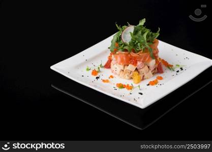 salad in a white square plate on a black background. dish on black background