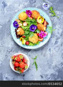 Salad leaves with strawberries,herbs and flowers. Fashionable summer herbal salad with grilled cheese, strawberries and flowers