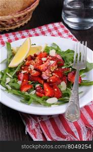 Salad of arugula and strawberries with crushed peanuts, almonds