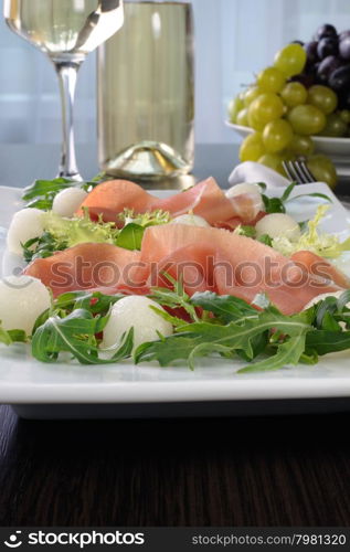 Salad of arugula, lettuce, ham with melon