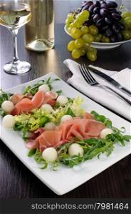 Salad of arugula, lettuce, ham with melon