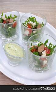Salad of arugula with cherry tomatoes, capers and feta in a glass