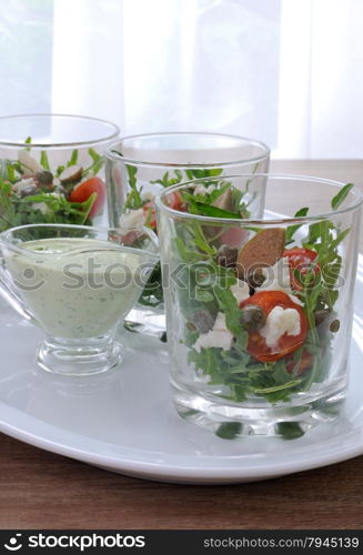 Salad of arugula with cherry tomatoes, capers and feta in a glass