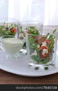 Salad of arugula with cherry tomatoes, capers and feta in a glass