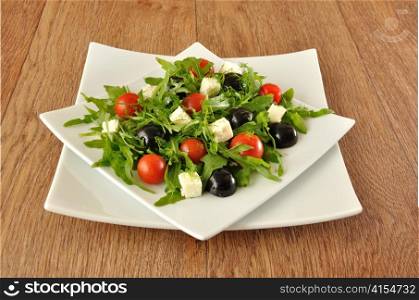 Salad of arugula with cherry tomatoes, slices of cheese and grapes