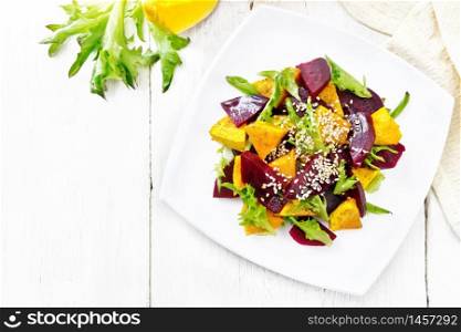 Salad of baked pumpkin, boiled beets, arugula, seasoned with vinegar, spices, orange juice and vegetable oil in a plate, napkin on wooden board background from above