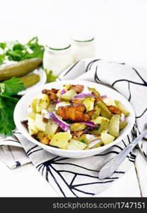 Salad of boiled potatoes, fried bacon, red onion and pickled cucumbers, seasoned with grain mustard, spices and vegetable oil in a plate on towel against wooden board background