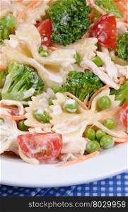 Salad of broccoli, peas, carrots, pasta, cherry tomatoes, slices of chicken in milk sauce