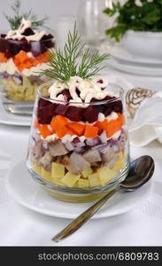 Salad of chopped herring with onions, potatoes, beets, carrots, seasoned with yogurt sauce in a glass