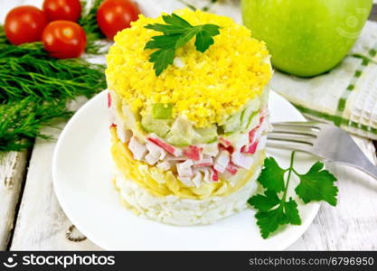 Salad of crab meat, cheese, eggs and apples in a plate, napkin, dill on the background light wooden boards