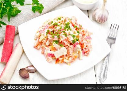 Salad of crab sticks, cheese, garlic and tomatoes, dressed with mayonnaise, napkin and parsley on the background of a light wooden board