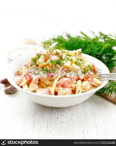 Salad of crab sticks, cheese, garlic, eggs and tomatoes, dressed with mayonnaise in a plate, towel and parsley on the background of a light wooden board