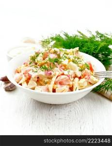 Salad of crab sticks, cheese, garlic, eggs and tomatoes, dressed with mayonnaise in a plate, towel and parsley on the background of a light wooden board