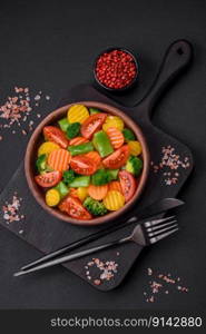 Salad of fresh and steamed vegetables cherry tomatoes, broccoli, carrots and asparagus beans on a dark concrete background