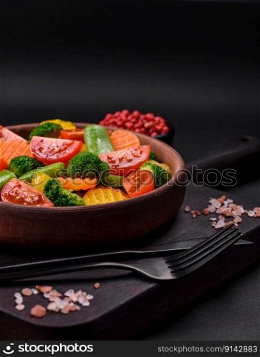 Salad of fresh and steamed vegetables cherry tomatoes, broccoli, carrots and asparagus beans on a dark concrete background