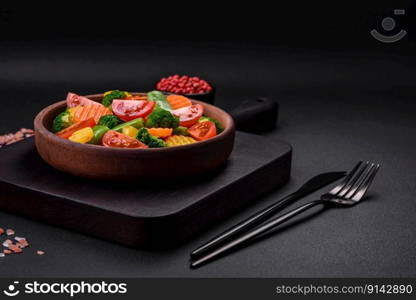 Salad of fresh and steamed vegetables cherry tomatoes, broccoli, carrots and asparagus beans on a dark concrete background