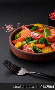 Salad of fresh and steamed vegetables cherry tomatoes, broccoli, carrots and asparagus beans on a dark concrete background