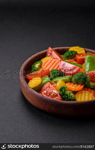 Salad of fresh and steamed vegetables cherry tomatoes, broccoli, carrots and asparagus beans on a dark concrete background