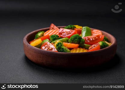 Salad of fresh and steamed vegetables cherry tomatoes, broccoli, carrots and asparagus beans on a dark concrete background