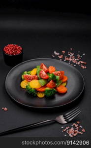 Salad of fresh and steamed vegetables cherry tomatoes, broccoli, carrots and asparagus beans on a dark concrete background