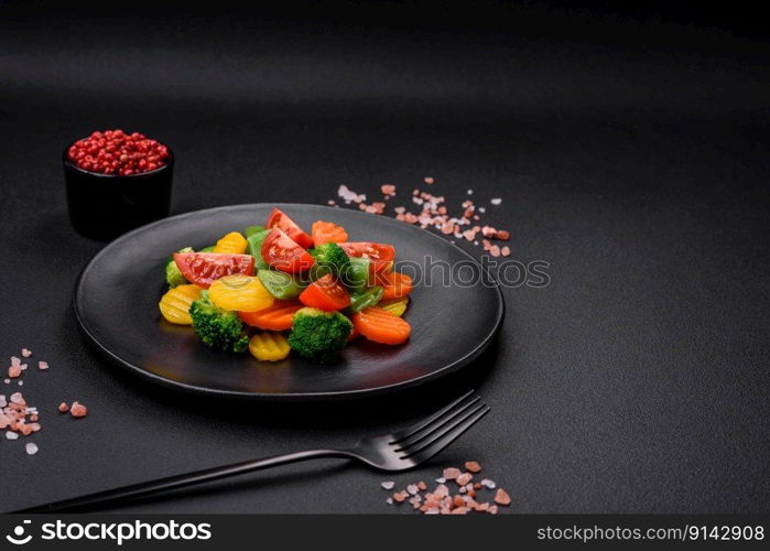 Salad of fresh and steamed vegetables cherry tomatoes, broccoli, carrots and asparagus beans on a dark concrete background