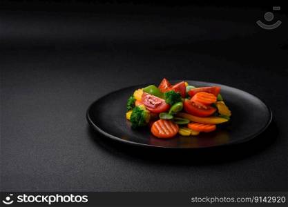 Salad of fresh and steamed vegetables cherry tomatoes, broccoli, carrots and asparagus beans on a dark concrete background