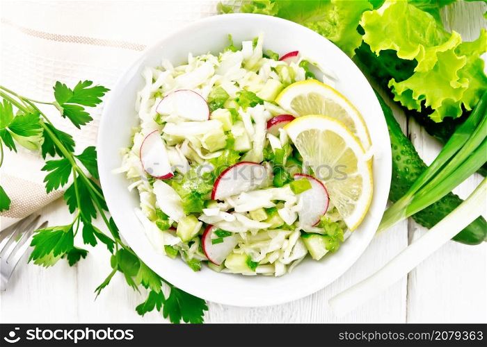 Salad of fresh cabbage, radish, lettuce, cucumber and green onion salad dressed with vegetable oil in a plate, napkin and parsley on wooden board background