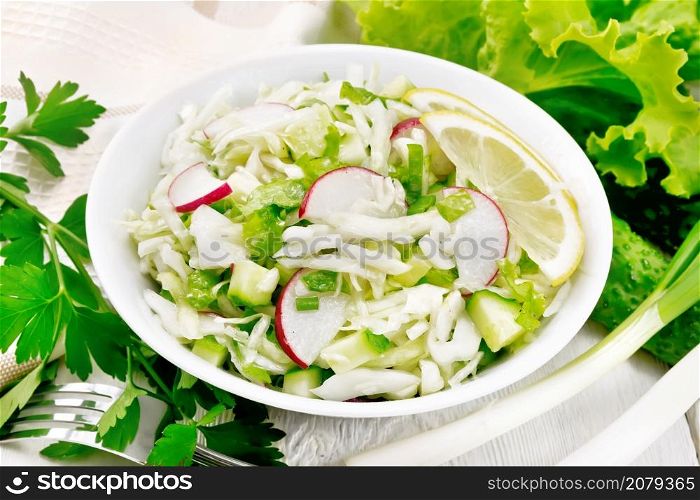 Salad of fresh cabbage, radish, lettuce, cucumber and green onion salad dressed with vegetable oil in a plate, napkin and parsley on white wooden board background