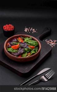 Salad of fresh cherry tomatoes, arugula, spinach, young beet leaves and other greens on a dark concrete background