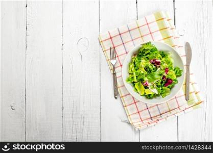 salad of fresh greens on a napkin. On a white wooden background.. salad of fresh greens on a napkin.