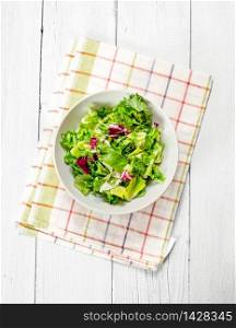 salad of fresh greens on a napkin. On a white wooden background.. salad of fresh greens on a napkin.