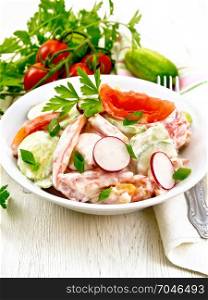 Salad of fresh tomatoes, cucumbers and radish with green onions and parsley, flavored with mayonnaise and sour cream in a plate, a towel on the background of a light wooden board