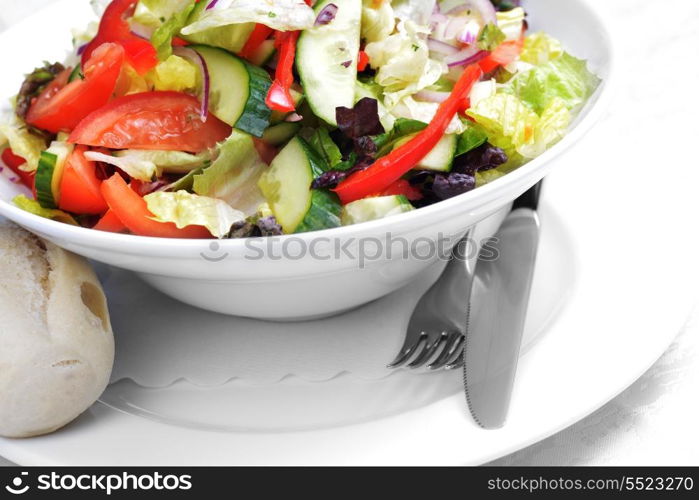 salad of fresh vegetable with bun on white dish.