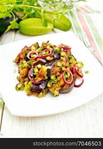 Salad of fried eggplant, fresh and pickled cucumber with red onion, seasoned with vegetable oil and spicy sauce in a plate, a towel on the background of a light wooden board